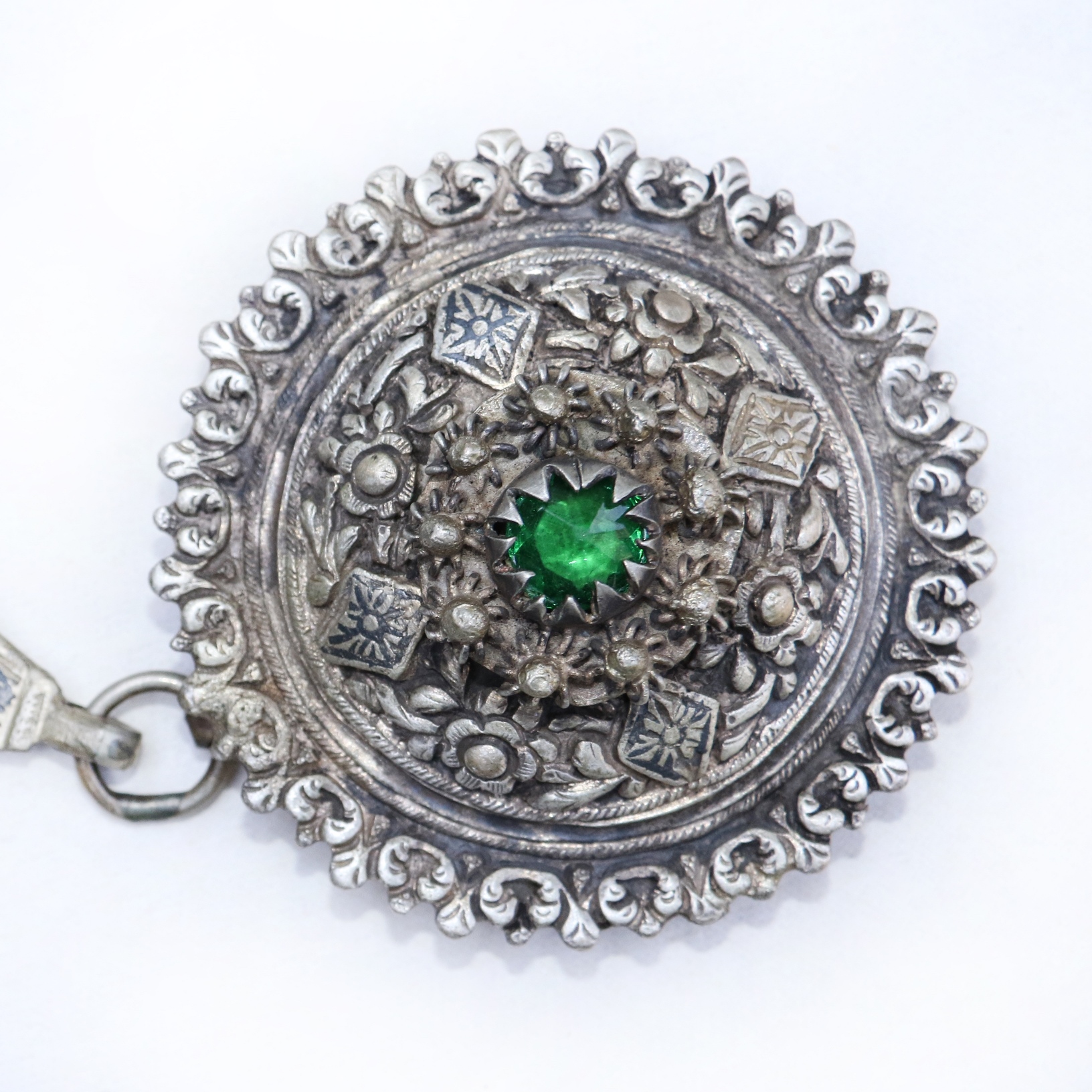 Ornate brooch with built-in green stone.