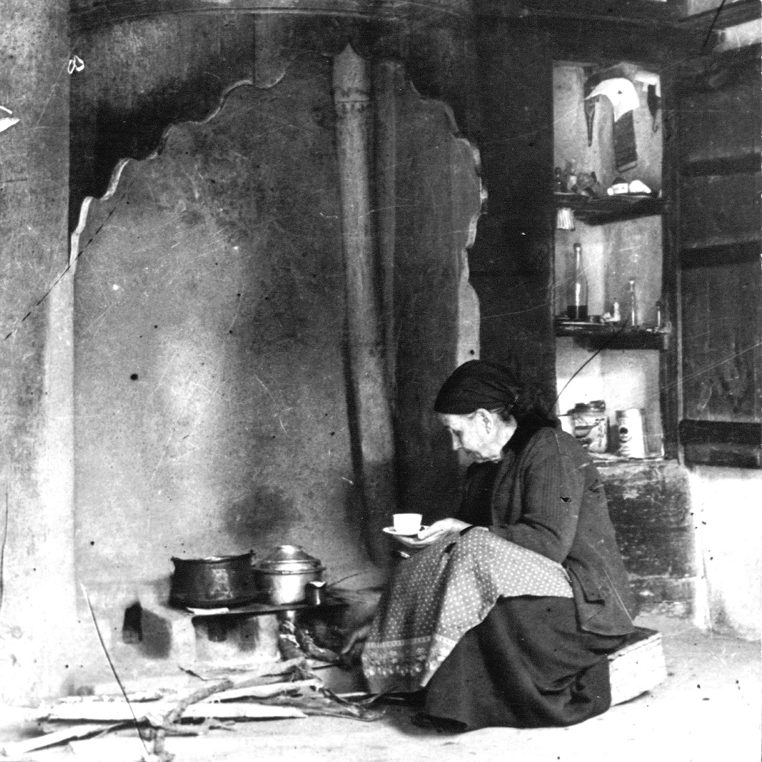Жена готви на домашно огнище - черно-бяла снимка.