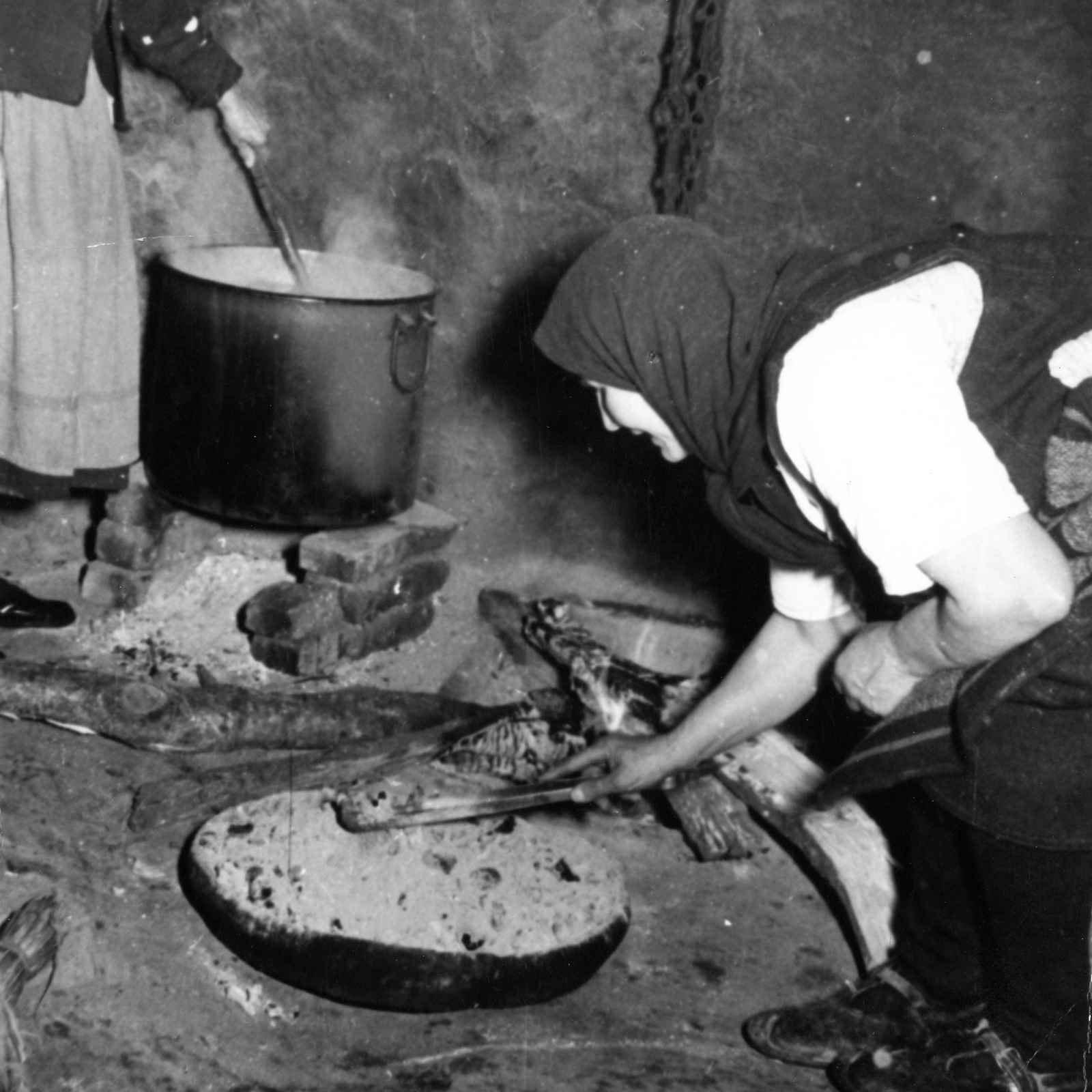 Жена разпалва домашно огнище - черно-бяла снимка.